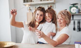 scintille di festa. madre, nonna e figlia che si divertono in cucina foto