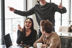 digita il tuo testo su quell'adesivo. divertirsi nella stanza dell'ufficio. colleghi amichevoli che giocano e celebrano il successo foto