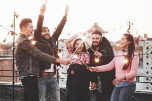 celebrare le feste. giocando con le stelle filanti sul tetto. gruppo di giovani bellissimi amici foto