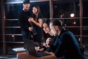 ragazzo dice cose importanti a una donna. team di giovani imprenditori lavora al loro progetto di notte in ufficio foto