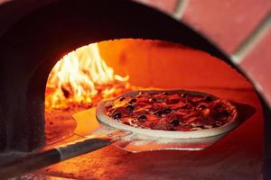 pizza sullo showel. fuoco che brucia nella fornace. vista ravvicinata del legno in fiamme foto