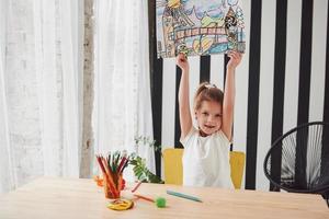 guarda cosa ho fatto la bambina carina della scuola d'arte mostra i suoi primi dipinti disegnati con matite e pennarelli foto