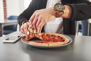 prendendo fetta. immagine di una deliziosa pizza preparata con anelli di salsiccia e olive foto