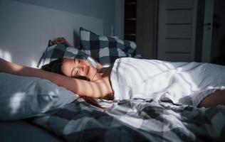 non c'è bisogno di andare al lavoro oggi. bella giovane donna sdraiata sul letto al mattino nella sua stanza foto