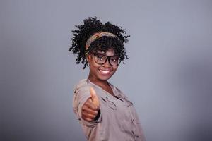 mostrando il pollice in su. concezione del successo. attraente donna afroamericana in abiti casual in studio foto