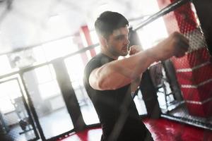 l'uomo forte sta facendo boxe in palestra dietro il recinto. fa esercizio quotidiano foto