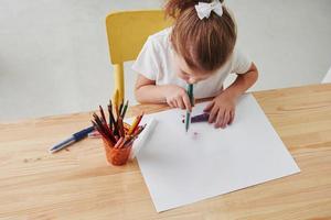 una sorta di tecnica artistica. la bambina carina della scuola d'arte disegna i suoi primi dipinti con matite e pennarelli foto