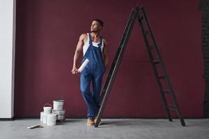 sguardo serio. il giovane lavoratore afroamericano in uniforme blu ha un lavoro da fare foto