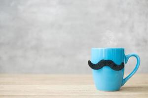 tazza di caffè blu o tazza da tè con decorazioni di baffi neri sul tavolo. spazio vuoto per la copia del testo. novembre blu, felice festa del papà e concetto di giornata internazionale degli uomini foto