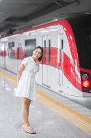 donna felice in attesa del treno alla stazione dei trasporti pubblici. concetto turistico e di viaggio foto