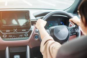 autista donna che guida un'auto sulla strada, volante di controllo manuale in un'automobile elettrica moderna. concetti di viaggio, viaggio e trasporto di sicurezza foto