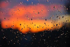 gocce d'acqua cristallina sul vetro della finestra con un bellissimo tramonto come sfondo foto