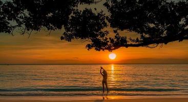 vista posteriore della siluetta della donna sexy che guarda il bel tramonto sulla spiaggia del paradiso tropicale. ragazza felice indossare bikini e cappello di paglia rilassanti vacanze estive. viaggio di vacanza. vibrazioni estive. vita pacifica. foto