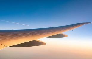 ala dell'aereo sopra la città. aereo che vola sul cielo blu. vista panoramica dalla finestra dell'aeroplano. volo di una compagnia aerea commerciale al mattino con la luce del sole. ala dell'aereo sopra le nuvole. concetto di meccanica di volo. foto