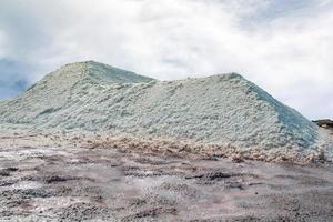 salina salata con cielo e nuvole. mucchio di sale marino biologico. materia prima di sale industriale. sale dell'oceano. minerale di cloruro di sodio. evaporazione e cristallizzazione dell'acqua di mare. fonte di iodio. foto