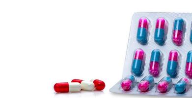 capsule antibiotiche rosso-bianche e granuli antimicotici rosa-blu in capsule in blister su sfondo bianco antibiotico resistenza ai farmaci e uso di farmaci antimicrobici con ragionevole. foto