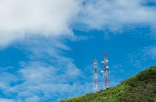 torre delle telecomunicazioni sulla montagna e albero verde con cielo blu. antenna sul cielo blu. polo radio e satellitare. Tecnologia della comunicazione. settore delle telecomunicazioni. rete mobile o di telecomunicazione 4g. foto