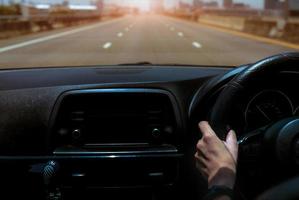 volante che tiene la mano del conducente per l'auto di controllo. vista interna dell'auto. cruscotto e parabrezza. guida di auto su strada di cemento in città. vista prospettica auto in autostrada. banda intelligente per indossare la mano del conducente foto