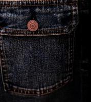 messa a fuoco selettiva sulla tasca della giacca di jeans denim nel negozio di abbigliamento. tasca della giacca di jeans e struttura del bottone. industria tessile. jeans moda e concetto di shopping. concetto di abbigliamento. Vendo giubbotto di jeans. foto