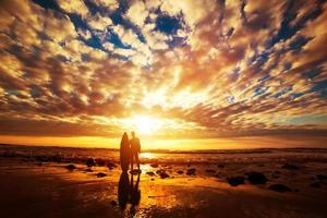 surfista in piedi con la sua tavola da surf sulla spiaggia al tramonto sull'oceano foto