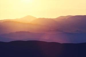 campi nebbiosi e colline rurali durante il tramonto. foto