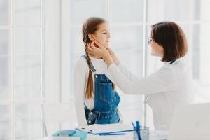 la foto del pediatra femminile esamina la gola del bambino, essendo un pediatra professionista qualificato, consulta il bambino su come prevenire la tonsillite, fornisce un buon trattamento e cura. concetto di controllo medico.