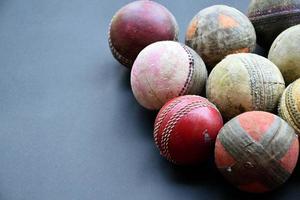 vecchie attrezzature per lo sport di cricket da allenamento su pavimento scuro, palla di cuoio, wicket, casco e mazza di legno, messa a fuoco morbida e selettiva, tradizionali amanti dello sport di cricket in tutto il mondo. foto