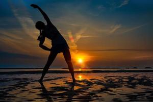 ragazza pratica fitness da sola in un'alba in spiaggia foto