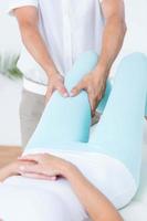 Fisioterapista che fa massaggio alle gambe al suo paziente foto