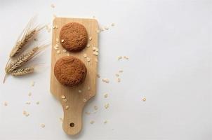 biscotti su una tavola di legno con fiocchi d'avena su sfondo bianco, banner, vista dall'alto foto