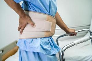 paziente della signora asiatica che indossa cintura di supporto per il dolore alla schiena per lombare ortopedico con deambulatore. foto