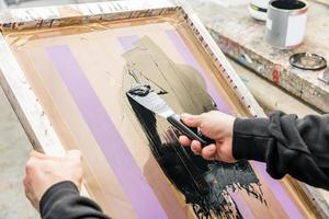 uomo che tergi serigrafia in un'officina. serigrafia foto