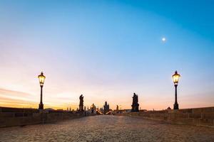 ponte charles all'alba, praga, repubblica ceca. statue drammatiche e torri medievali. foto