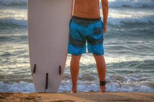 surfista con tavola da surf in piedi sulla sabbia foto
