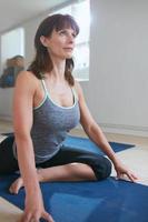 donna adatta che fa yoga in palestra foto
