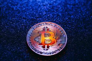 una moneta con logo bitcoin su sfondo blu foto