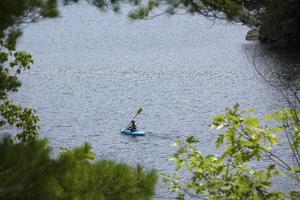 giovane donna in kayak, acqua in sunapee, New Hampshire, Horizonta foto