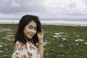 una giovane ragazza asiatica sulla spiaggia sorride alla telecamera a gunungkidul, in indonesia foto