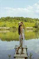 giovane donna in piedi sul molo di legno al lago calmo foto