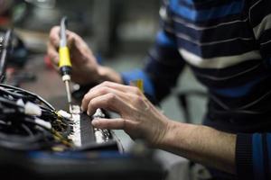 uomo lavoratore industriale cavi di saldatura di apparecchiature di produzione in una fabbrica. messa a fuoco selettiva foto