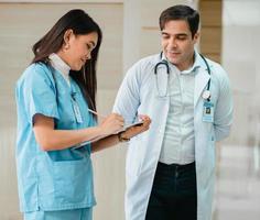 studentessa di medicina è sul posto di lavoro nell'apprendimento clinico con un medico maschio professionista presso l'ospedale della scuola di medicina. donna stagista medico tiene appunti sul lavoro di formazione con docente insegnante medico. foto