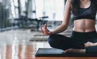 sport donna asiatica che pratica lezione di yoga, respirazione, meditazione, esercizio di ardha padmasana, allenamento in palestra foto