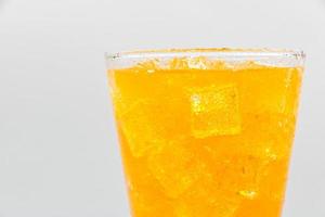 acqua frizzante arancione con ghiaccio in vetro su sfondo bianco. foto
