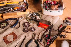 strumenti per la lavorazione del filo di rame fatti a mano sul tavolo con accessori. concetto di arte della gente dell'artigianato foto