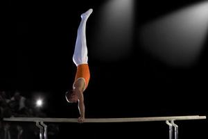 ginnasta maschio eseguendo verticale su barre parallele, vista laterale foto
