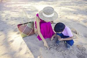 ragazzo asiatico e donna mamma che si rilassano sulla spiaggia tropicale, amano la libertà e l'aria fresca, indossando cappelli e vestiti eleganti. felice turista sorridente ai tropici in vacanza di viaggio foto