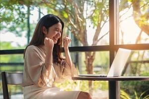 felicità successo donna d'affari asiatica felice durante l'utilizzo del computer portatile per il risultato aziendale foto