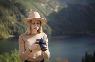 fotografo turista viaggiatore in piedi sulla cima verde sulla montagna tenendo in mano la fotocamera digitale foto