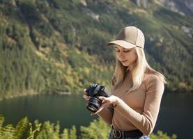 fotografo turista viaggiatore in piedi sulla cima verde sulla montagna tenendo in mano la fotocamera digitale foto