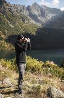 giovane fotografo che scatta fotografie con la fotocamera digitale in montagna.